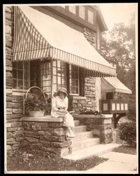 Una mujer sentada en la entrada de una casa, 1915
